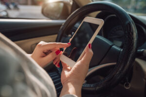 Lyft Accident Lawyer Athens GA - Mockup image of woman hand using mobile smartphone with blank screen while driving car and leaving home. clipping path.