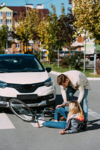Person helping up another person from the ground after being hit by a car while riding a bike and before calling a Bicycle Accident Lawyer Watkinsville GA